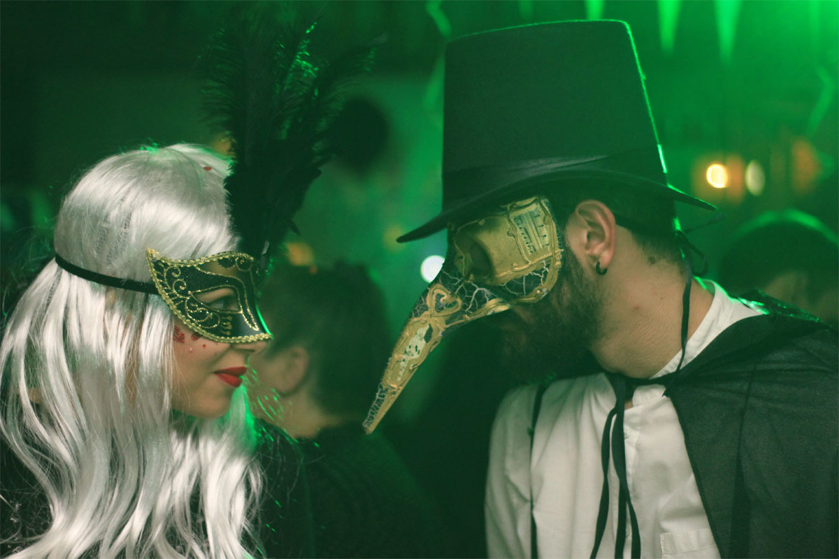 A couple wearing masks and costumes gazing at each other seductively
