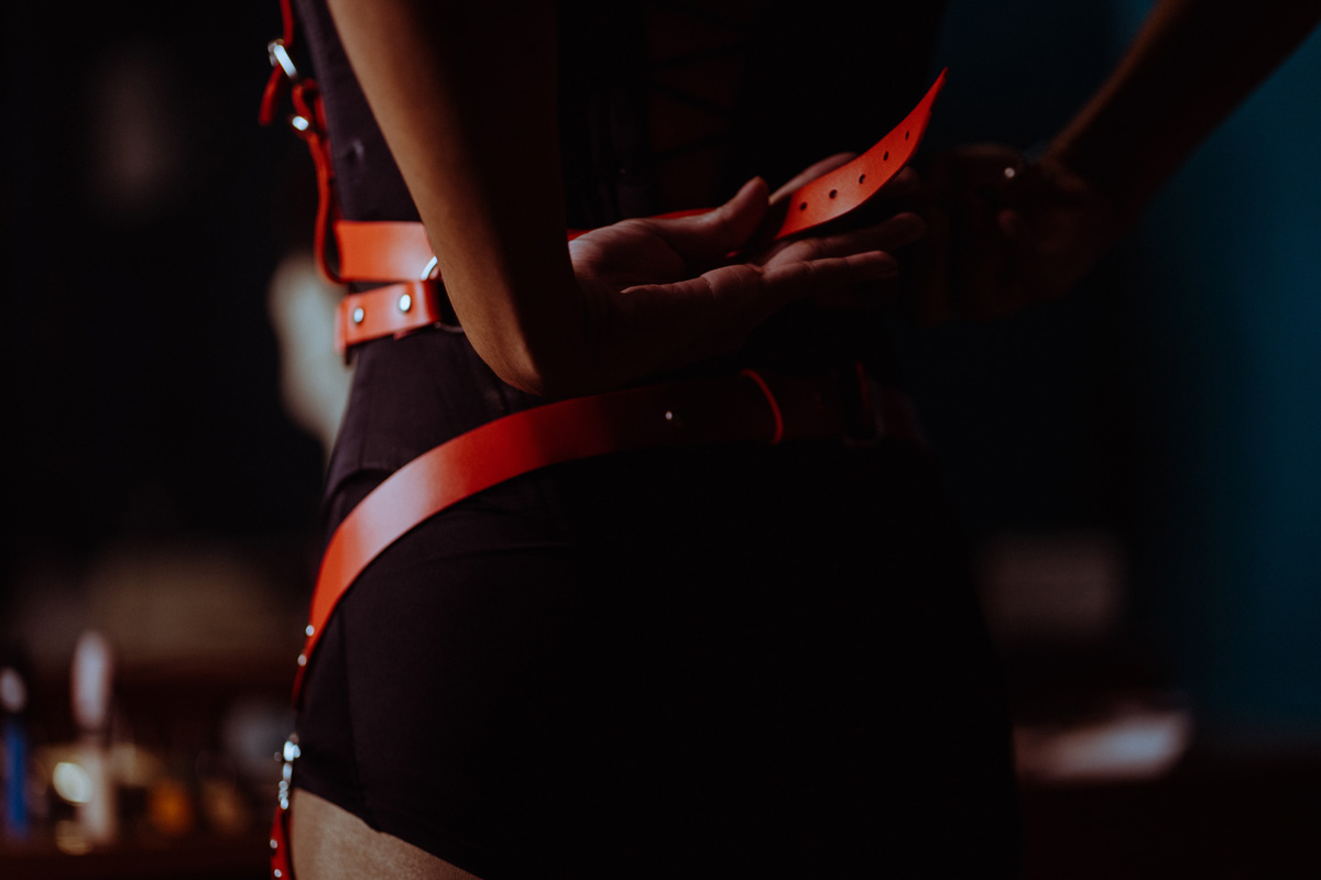Woman fastening BDSM harness around her waist